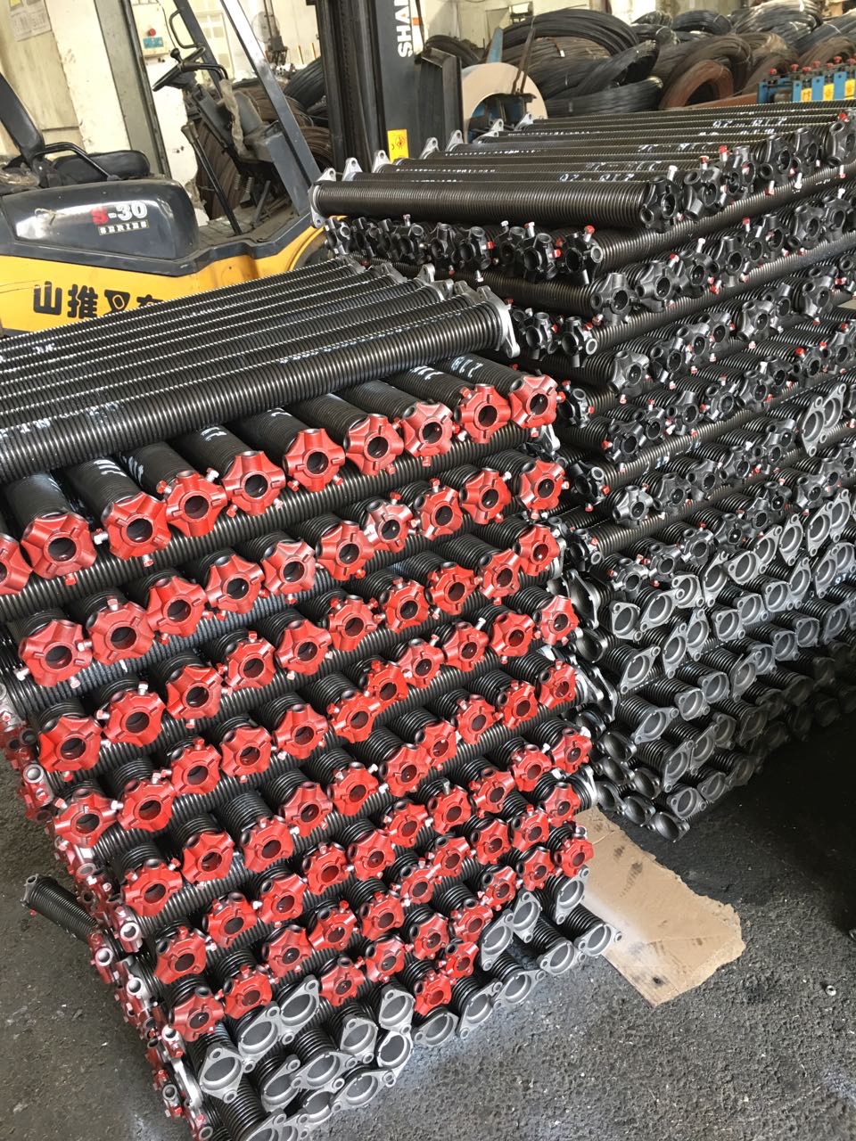Stacks of black torsion springs with red cast winding cones, ready for commercial door work